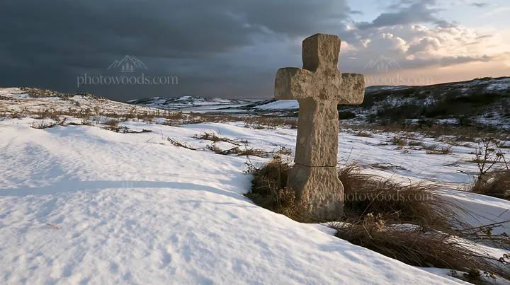 Stone Christian cross in snowy meadow at sunset - AI-generated stock image
